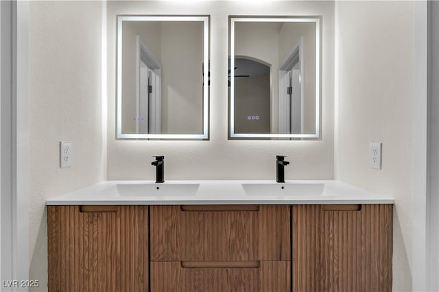 bathroom featuring a textured wall, double vanity, and a sink