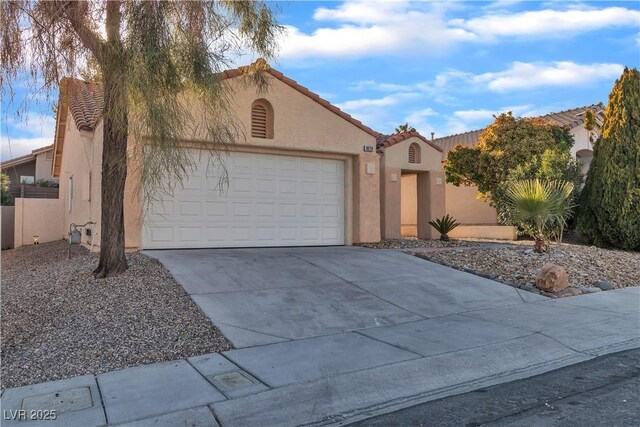 mediterranean / spanish house featuring driveway, a tiled roof, an attached garage, and stucco siding