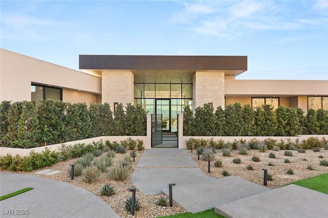 property entrance with stone siding, a gate, and stucco siding