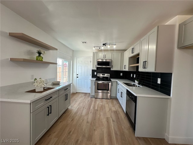 kitchen featuring a sink, appliances with stainless steel finishes, open shelves, and light countertops