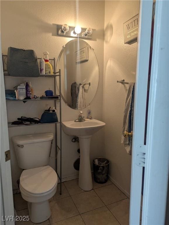 half bath with a sink, tile patterned flooring, and toilet