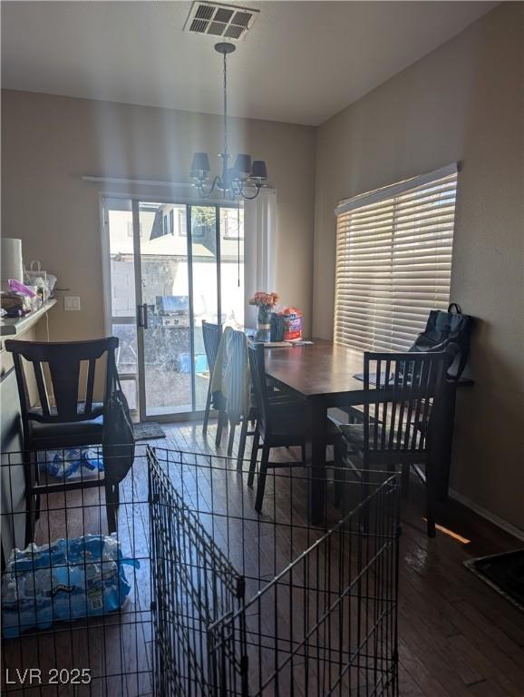 dining space with an inviting chandelier, baseboards, visible vents, and dark wood-type flooring