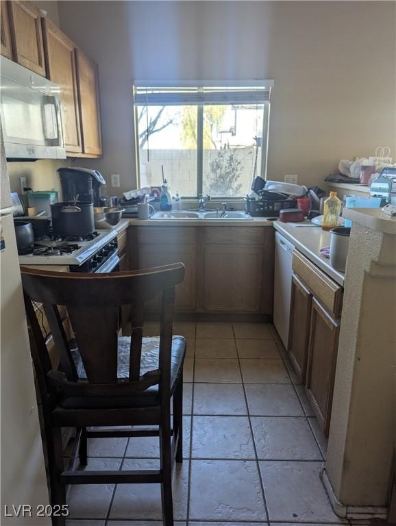 kitchen with dishwasher, light countertops, a sink, and freestanding refrigerator