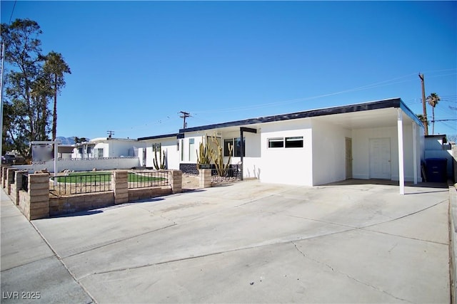 view of front of property with driveway, an attached carport, a fenced front yard, and stucco siding