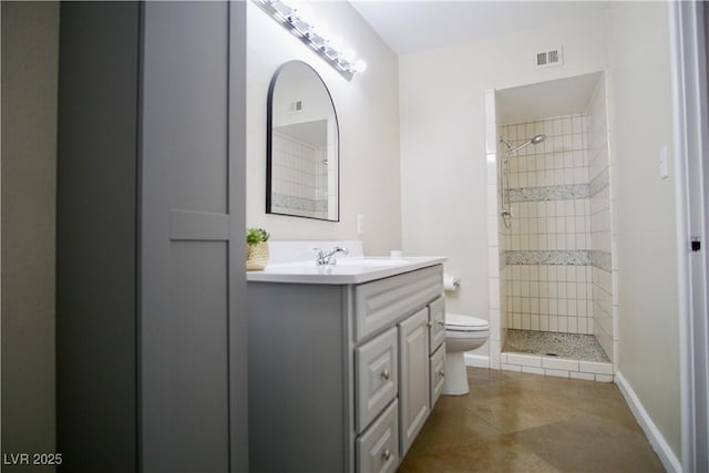 bathroom with visible vents, tiled shower, toilet, tile patterned flooring, and vanity