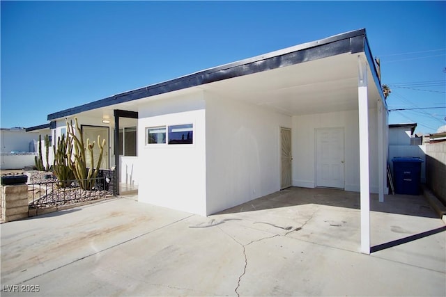 exterior space featuring a carport, driveway, fence, and stucco siding