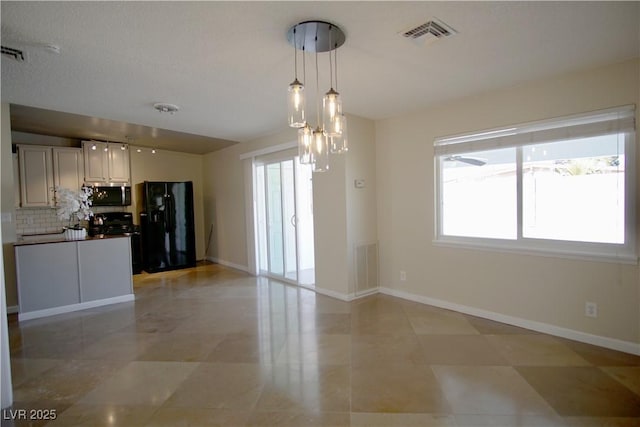 interior space with visible vents, dark countertops, black appliances, white cabinetry, and pendant lighting