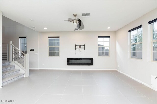 unfurnished living room featuring stairs, a glass covered fireplace, visible vents, and baseboards