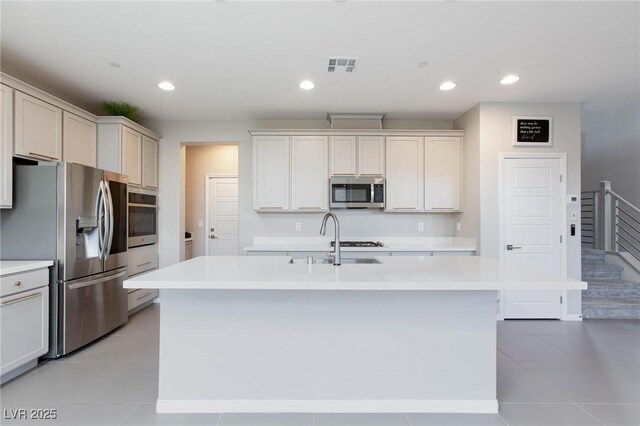 kitchen featuring light tile patterned floors, visible vents, a kitchen island with sink, stainless steel appliances, and light countertops