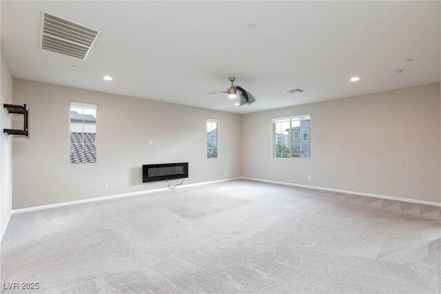 unfurnished living room with a glass covered fireplace, visible vents, and baseboards