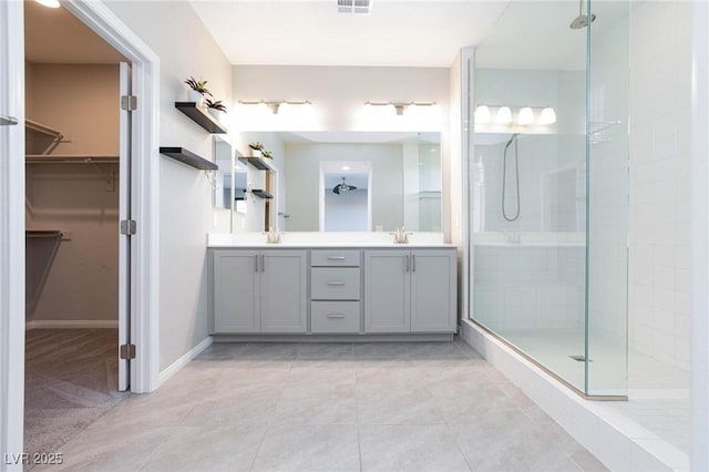 full bath featuring double vanity, a spacious closet, a walk in shower, and a sink