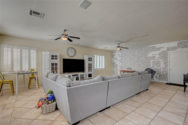 living area with ceiling fan, light tile patterned floors, visible vents, and baseboards