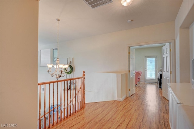 hall featuring a notable chandelier, visible vents, an upstairs landing, light wood-type flooring, and baseboards