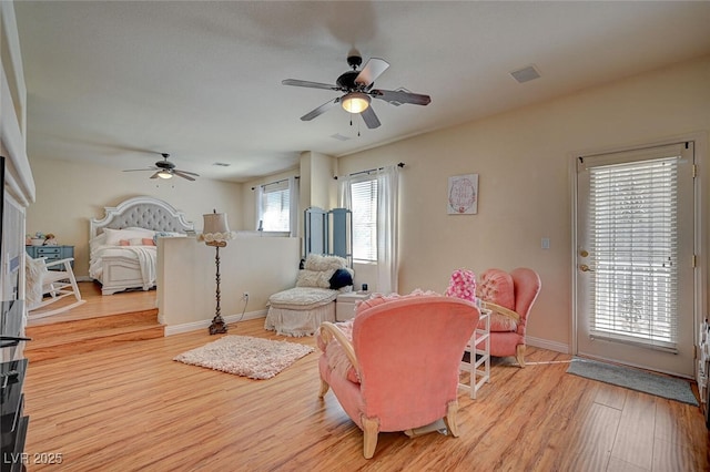 living room with visible vents, light wood-type flooring, a ceiling fan, and baseboards