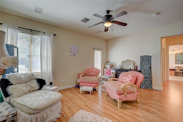 living area featuring a ceiling fan, light wood-type flooring, visible vents, and baseboards