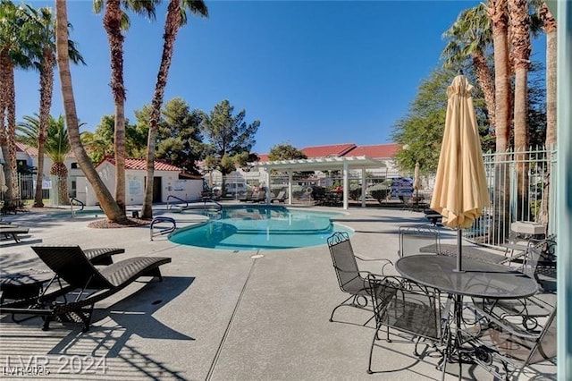 community pool with a patio area, fence, and a pergola