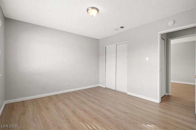 unfurnished bedroom featuring light wood-style floors, a closet, visible vents, and baseboards