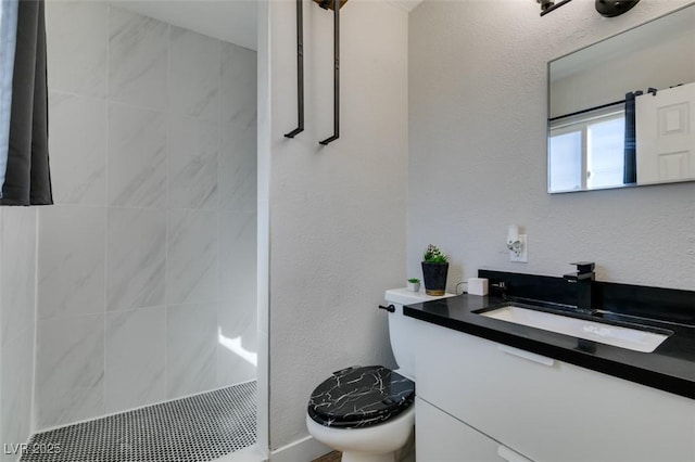 full bathroom featuring toilet, a textured wall, a shower stall, and vanity