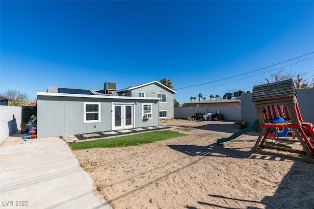 rear view of house featuring french doors, a playground, a fenced backyard, and central air condition unit