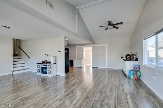 unfurnished living room featuring ceiling fan, light wood-style flooring, stairway, and visible vents