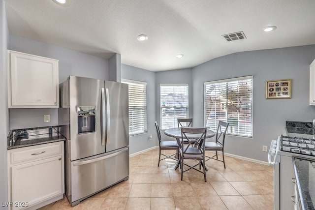 kitchen featuring visible vents, vaulted ceiling, stainless steel refrigerator with ice dispenser, gas range gas stove, and light tile patterned flooring