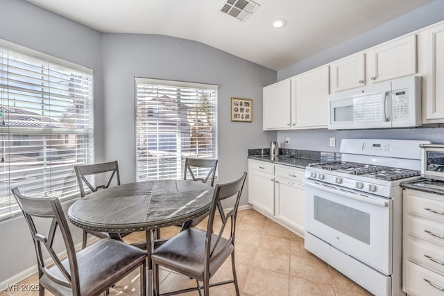 kitchen featuring lofted ceiling, light tile patterned floors, white appliances, visible vents, and white cabinetry