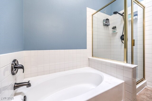 bathroom featuring a shower stall and a bath