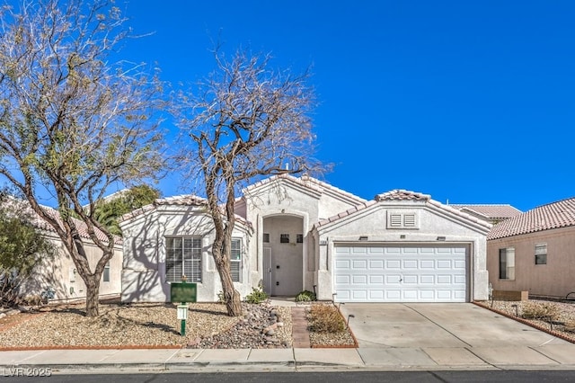 mediterranean / spanish home featuring driveway, stucco siding, an attached garage, and a tiled roof