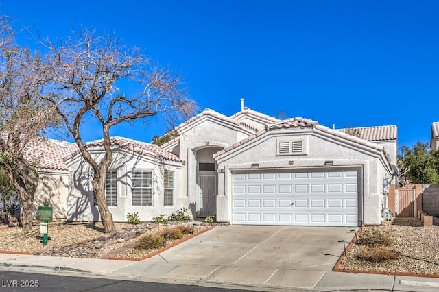 mediterranean / spanish-style house with driveway, a tile roof, a garage, and stucco siding