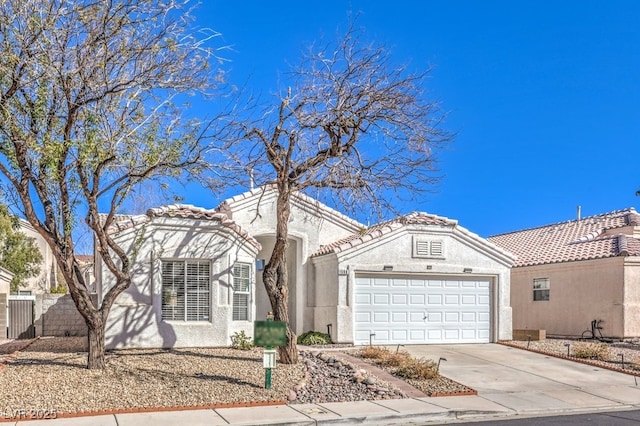 mediterranean / spanish home with an attached garage, stucco siding, concrete driveway, and a tiled roof