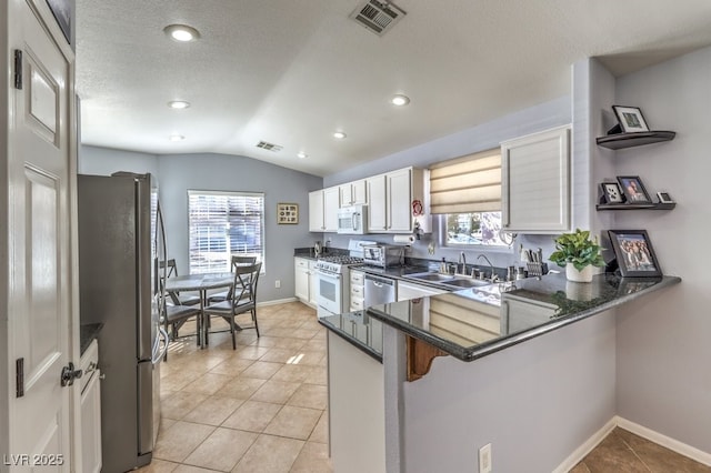 kitchen featuring appliances with stainless steel finishes, lofted ceiling, visible vents, and a sink