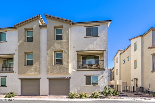 townhome / multi-family property featuring central air condition unit, an attached garage, fence, and stucco siding