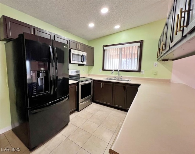 kitchen with light tile patterned floors, stainless steel appliances, light countertops, a sink, and dark brown cabinetry