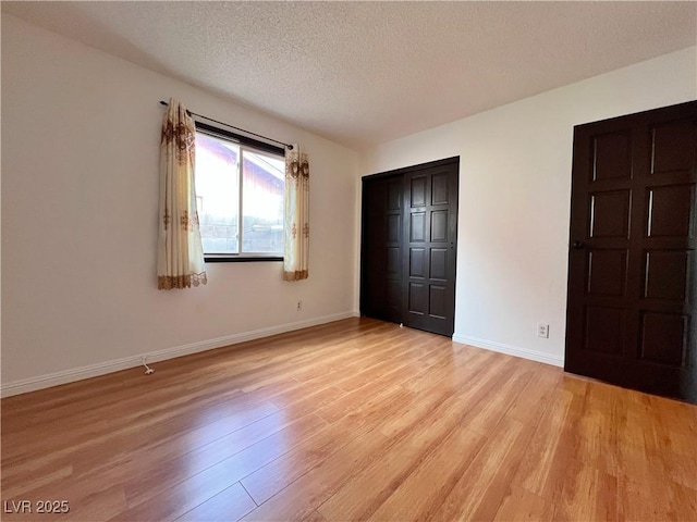 unfurnished bedroom with a textured ceiling, a closet, light wood-style flooring, and baseboards