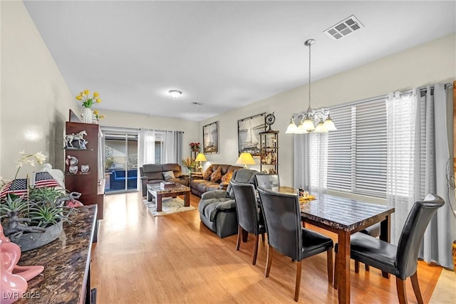 dining space featuring light wood finished floors, visible vents, and a notable chandelier