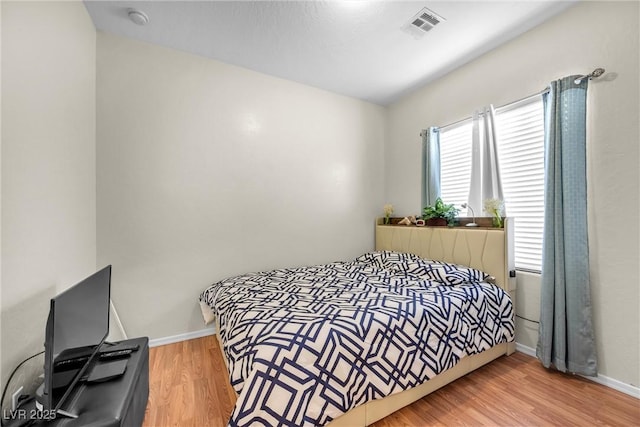 bedroom with light wood-type flooring, baseboards, and visible vents