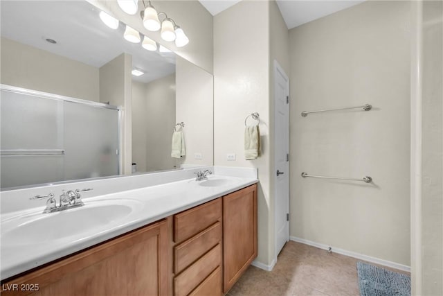 full bathroom with double vanity, tile patterned floors, a sink, and baseboards