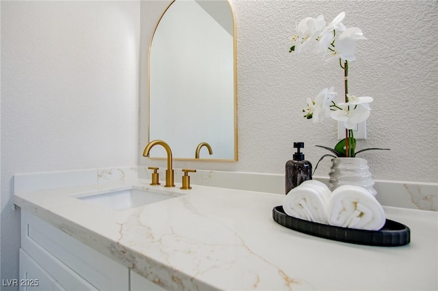 interior details featuring a textured wall and vanity