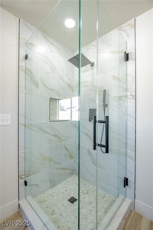 full bathroom with wood finished floors, a shower stall, and baseboards