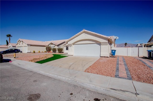 mediterranean / spanish house featuring a garage, driveway, a tiled roof, fence, and stucco siding