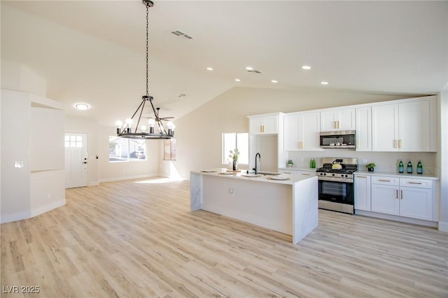 kitchen with stainless steel appliances, light countertops, visible vents, a kitchen island with sink, and white cabinetry