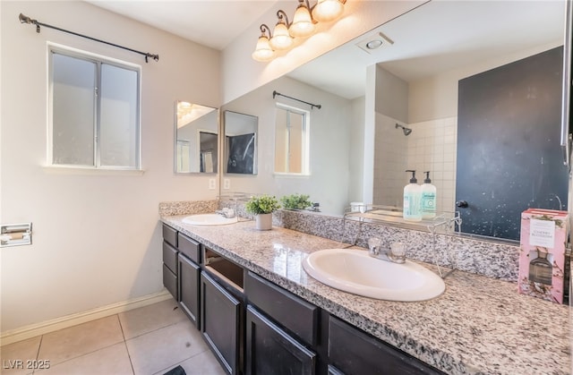 full bath with baseboards, double vanity, a sink, and tile patterned floors