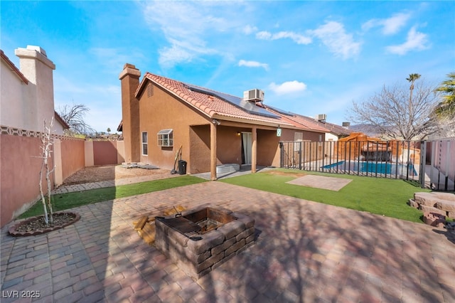 rear view of property with a fenced in pool, stucco siding, an outdoor fire pit, a patio area, and a fenced backyard