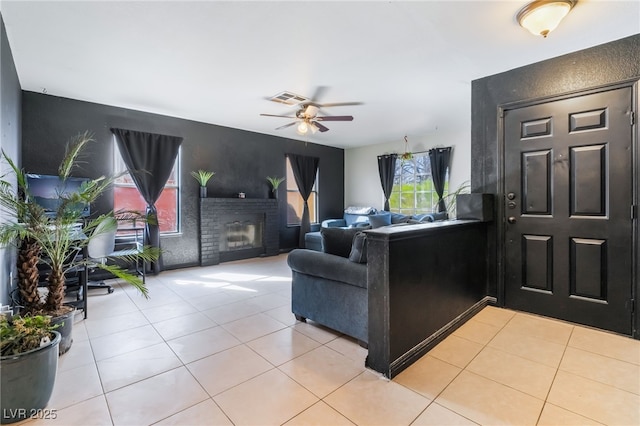 living area featuring a ceiling fan, a brick fireplace, visible vents, and light tile patterned floors