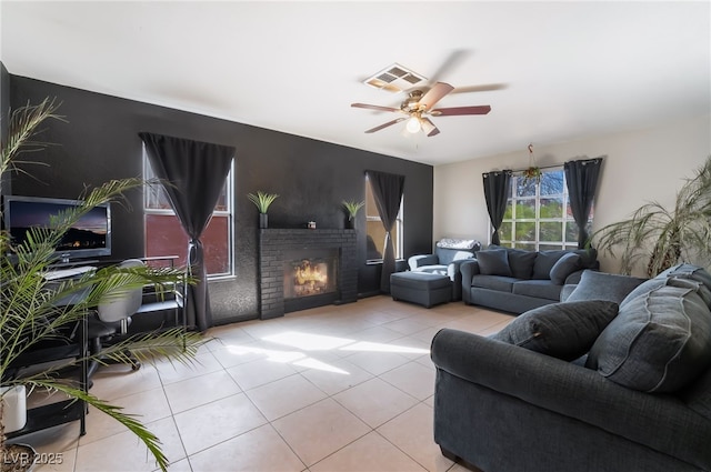 living area featuring ceiling fan, light tile patterned flooring, a brick fireplace, and visible vents