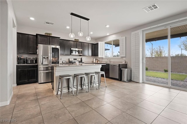 kitchen featuring visible vents, a kitchen island, a breakfast bar area, light countertops, and stainless steel appliances