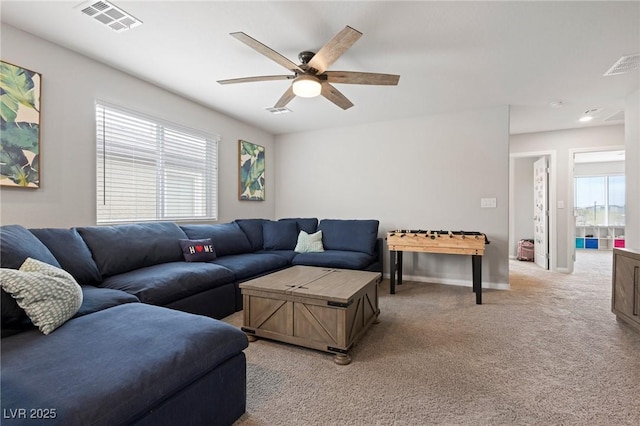 living area featuring visible vents, baseboards, light colored carpet, and ceiling fan