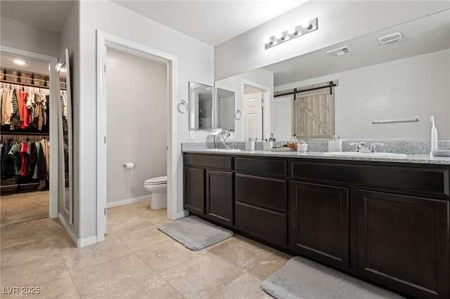 full bathroom featuring visible vents, double vanity, a sink, a spacious closet, and toilet