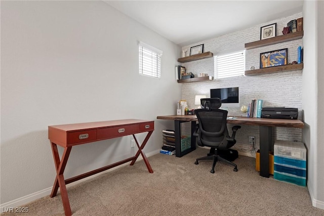 carpeted home office featuring baseboards and brick wall