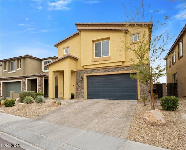 view of front of house with fence, stucco siding, a garage, stone siding, and decorative driveway